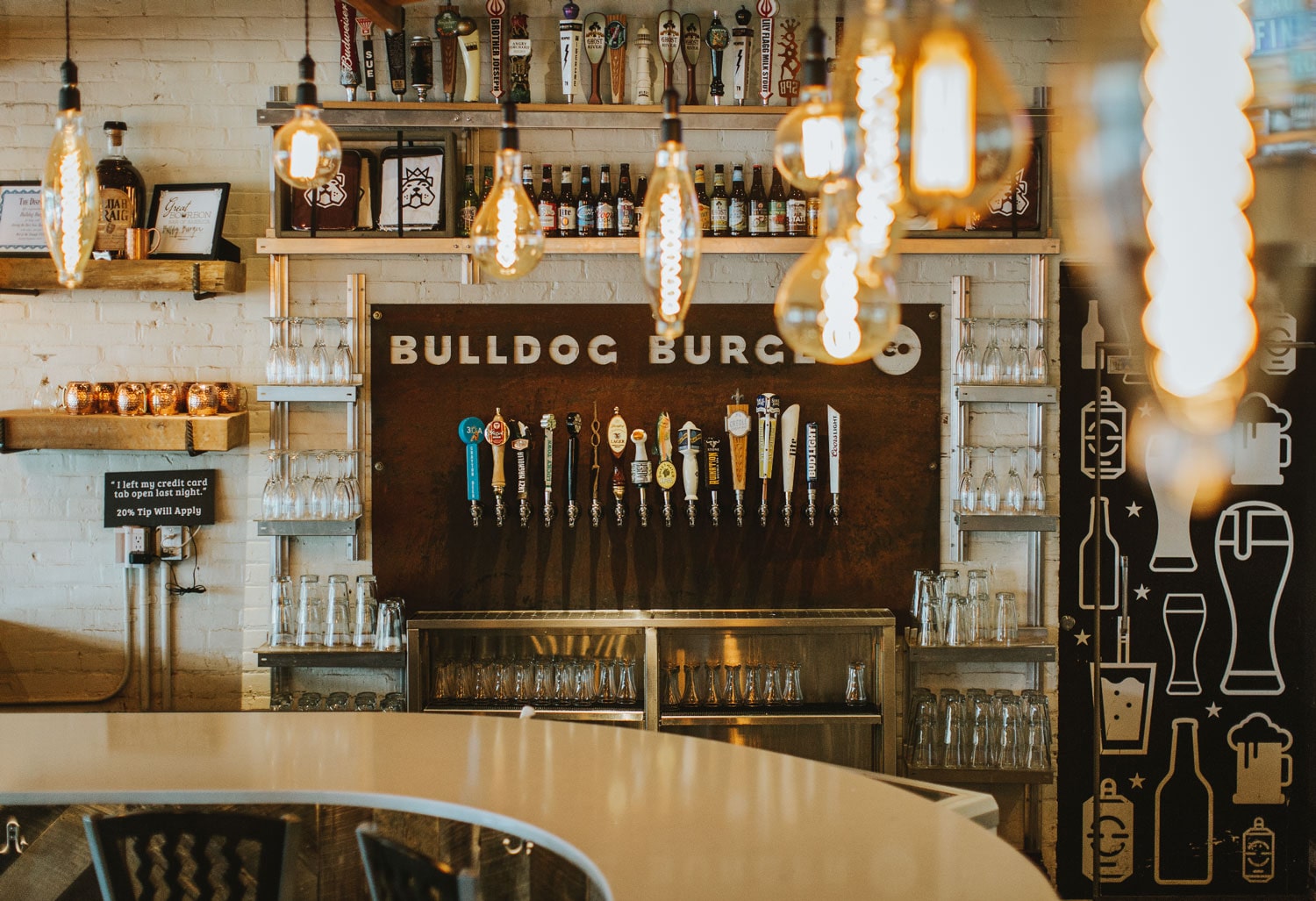 Beer tap wall with local craft brews and industrial vibe at Bulldog Burger Company restaurant, highlighting signature bar experience at all locations.